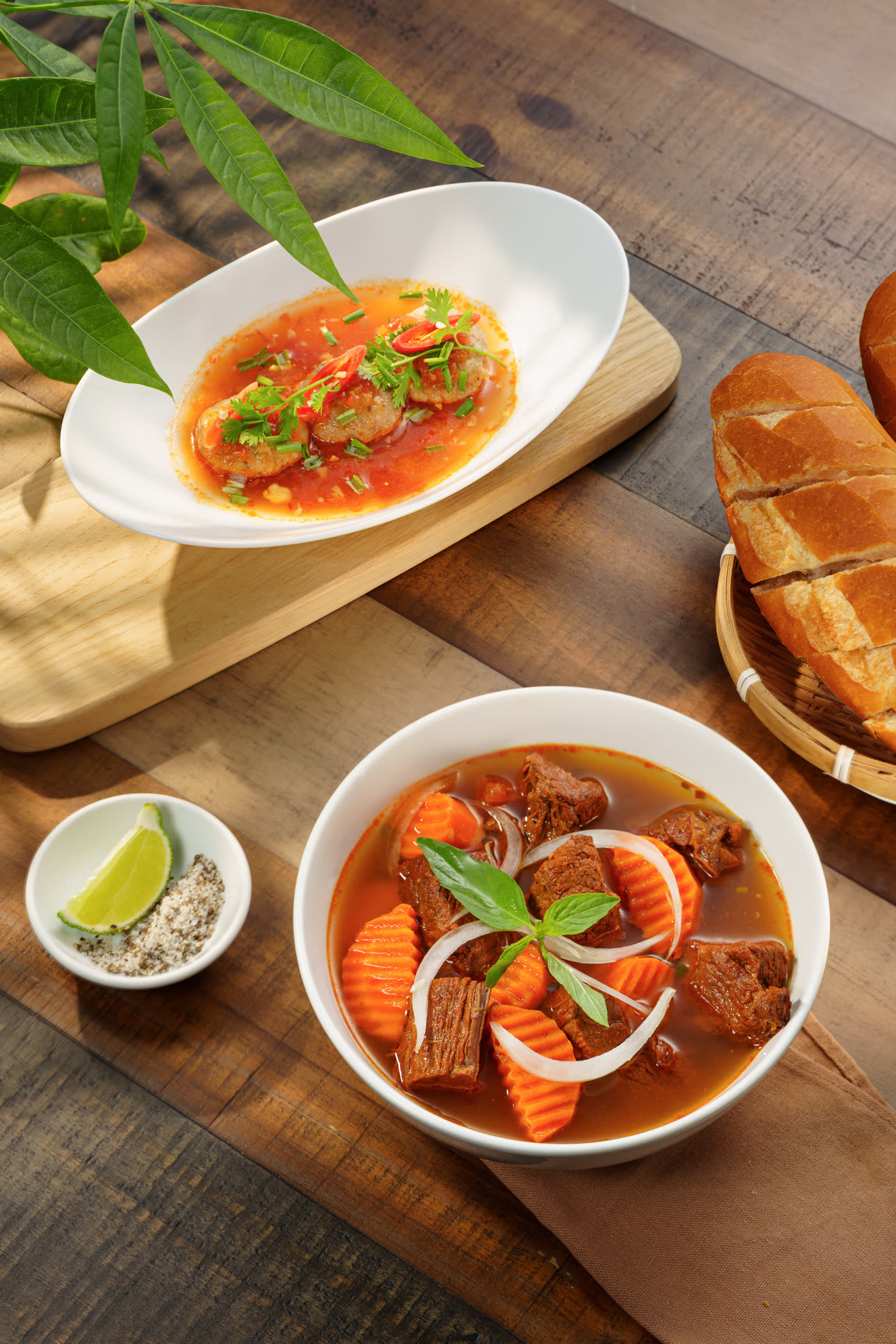 A bowl of Vietnamese beef stew, steam rising, with a plate of meatballs alongside