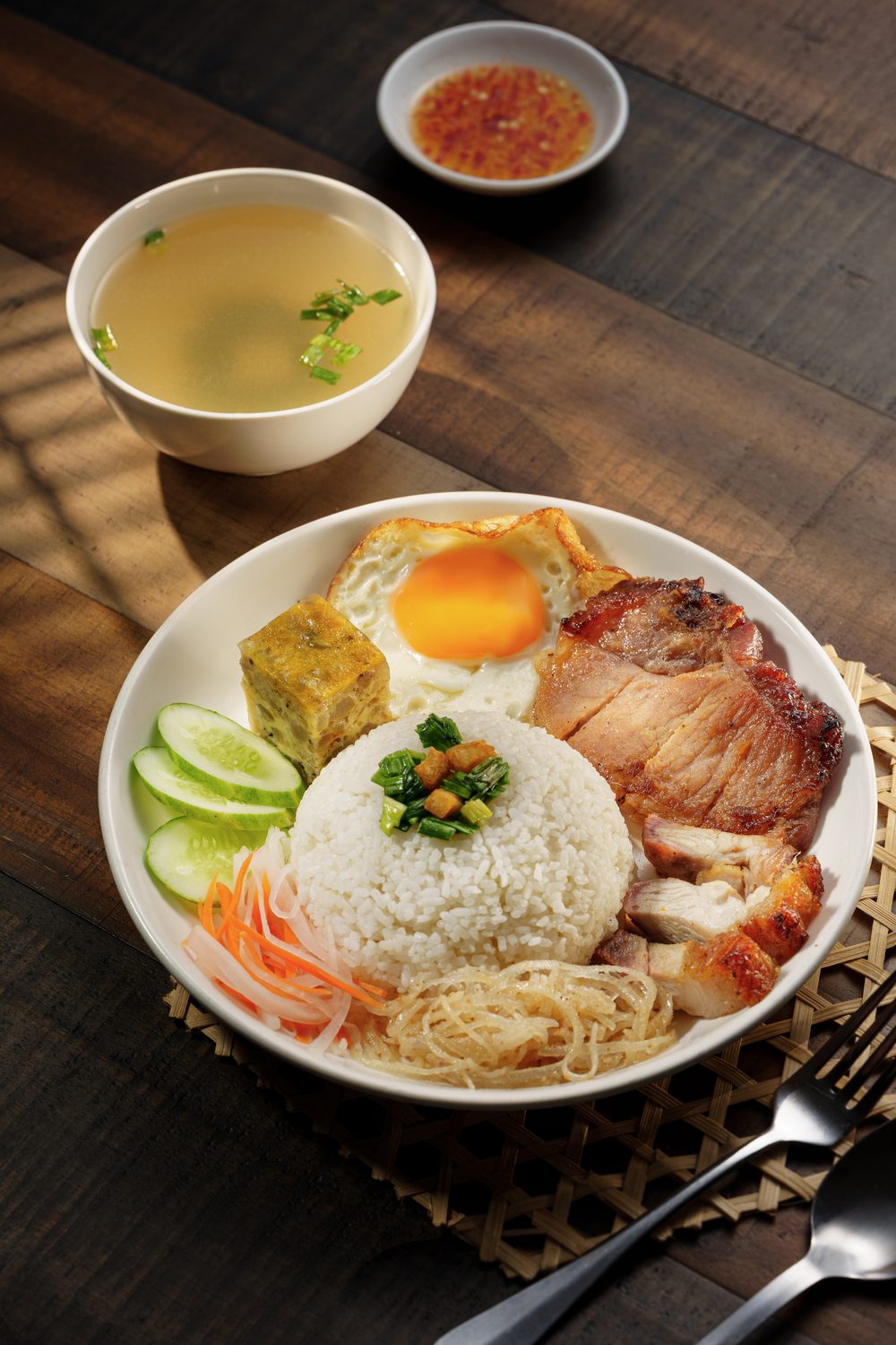 Broken rice plate with char-grilled pork chop, fried egg, steamed pork paste, cucumber and pickles