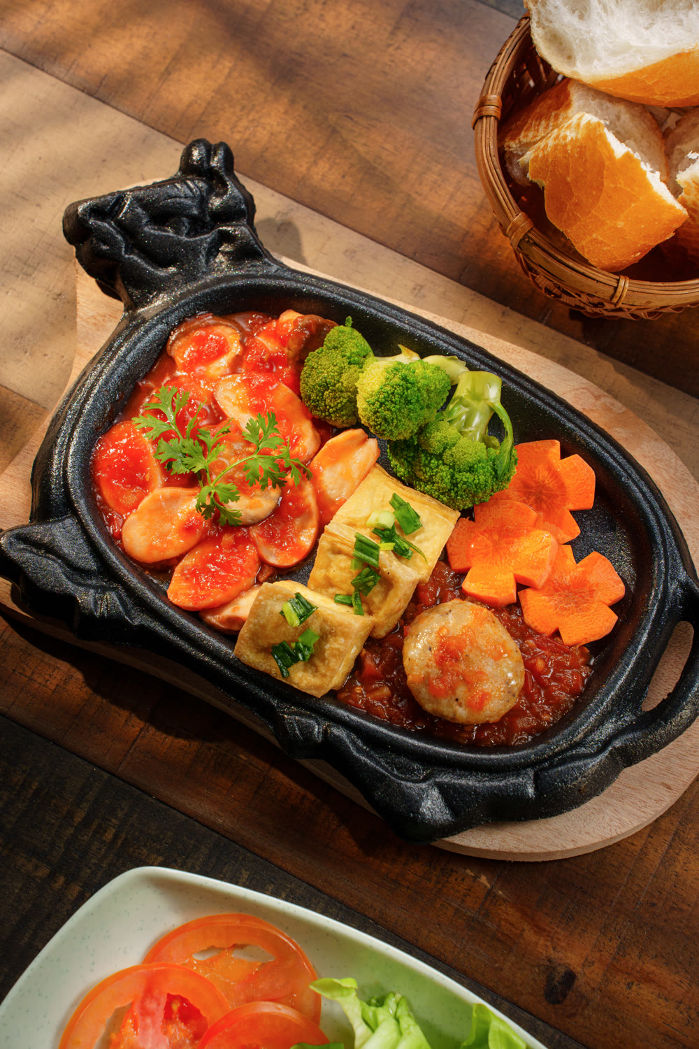 Vegan sizzling pan with tofu, veggie balls, broccoli and carrot in tomato sauce