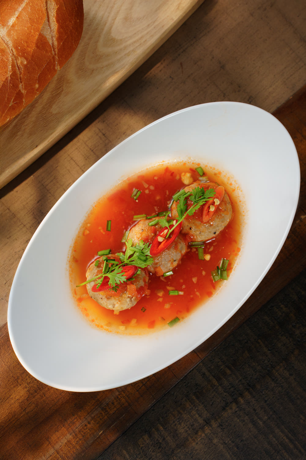 Pork meatballs in tomato broth, garnished with chilli and herbs