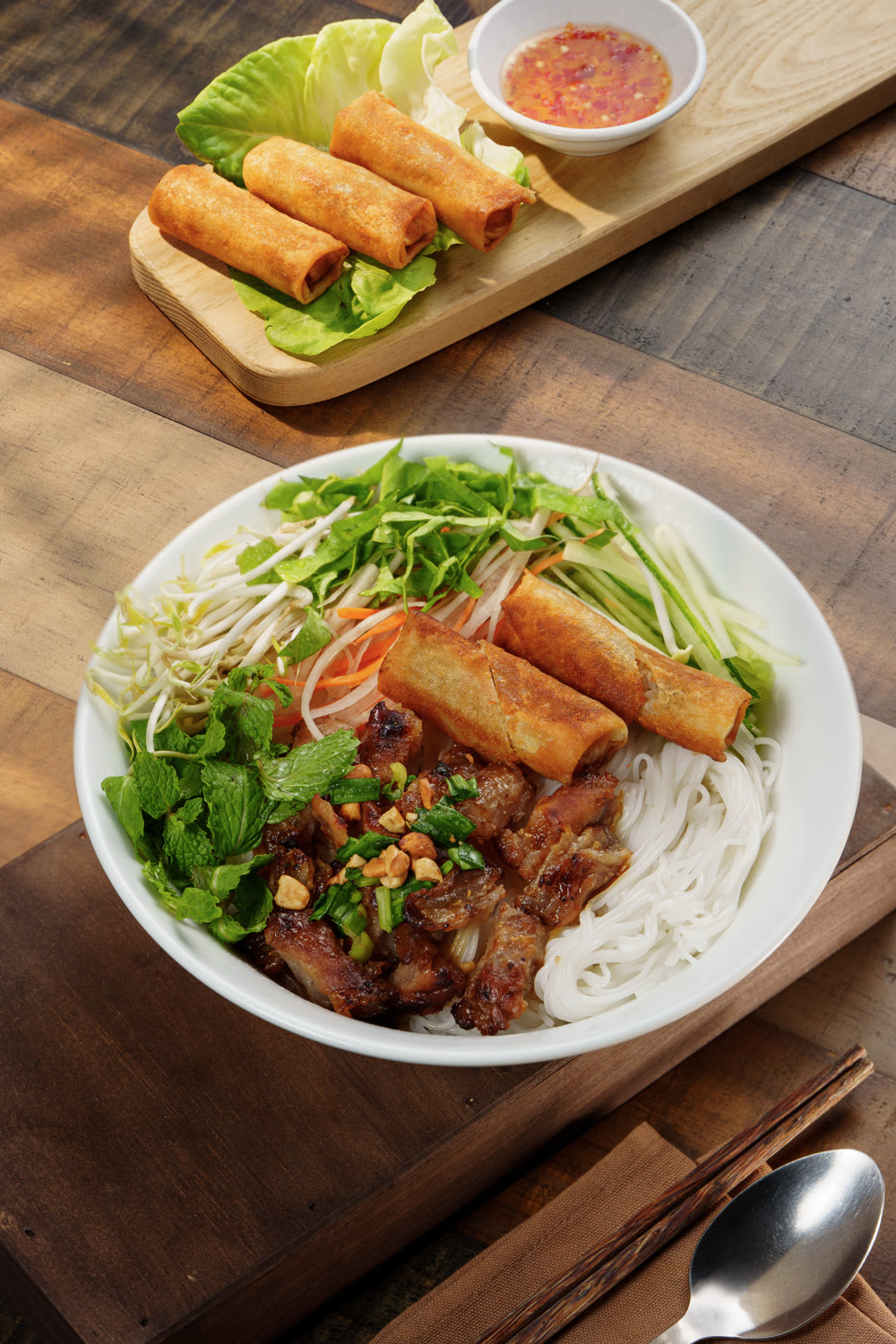 A vermicelli bowl with grilled pork, spring rolls and fresh herbs